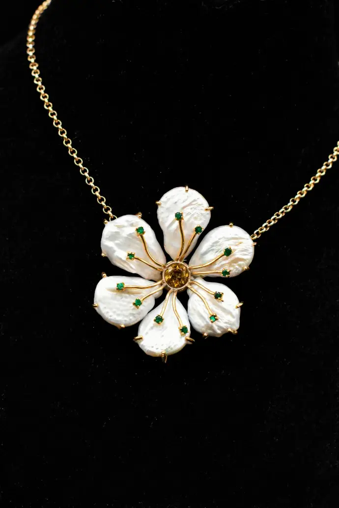 a necklace with white flowers on a gold chain